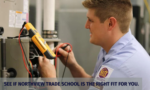 Male technician in a light-blue uniform tests electrical wiring with a handheld multimeter inside an equipment cabinet.